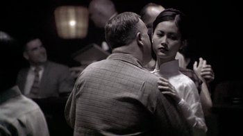 Movie still from “The Quiet American” (2002), directed by Phillip Noyce – A man and a woman are standing in a room together; Medium shot, Over the shoulder angle