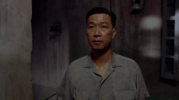 Movie still from “The Quiet American” (2002), directed by Phillip Noyce – A man standing in front of a cement wall; Close Up shot, Low angle