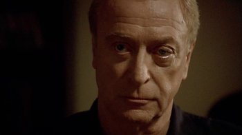 Movie still from “The Quiet American” (2002), directed by Phillip Noyce – An older man stares into the camera; Close Up shot, Over the shoulder angle