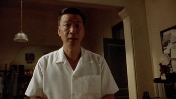 Movie still from “The Quiet American” (2002), directed by Phillip Noyce – An older man wearing a white shirt in front of a mirror; Medium shot, Low angle