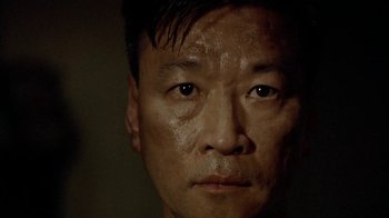 Movie still from “The Quiet American” (2002), directed by Phillip Noyce – A man's face in a dark room; Close Up shot, Low angle