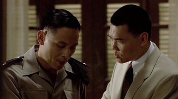 Movie still from “The Quiet American” (2002), directed by Phillip Noyce – Two men in suits talking to each other in front of a window; Close Up shot, Over the shoulder angle