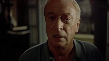 Movie still from “The Quiet American” (2002), directed by Phillip Noyce – An older man is looking into the camera; Close Up shot, Over the shoulder angle