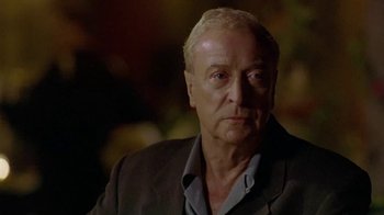 Movie still from “The Quiet American” (2002), directed by Phillip Noyce – An older man in a suit looking at the camera; Close Up shot, Over the shoulder angle