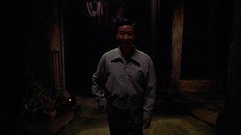 Movie still from “The Quiet American” (2002), directed by Phillip Noyce – A man standing in the dark in front of a building; Medium shot, High angle