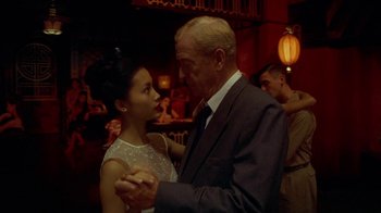 Movie still from “The Quiet American” (2002), directed by Phillip Noyce – An older man and a young woman dancing in front of a crowd; Close Up shot, Low angle