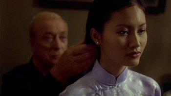 Movie still from “The Quiet American” (2002), directed by Phillip Noyce – An older man is helping an older woman with her hair; Close Up shot, Over the shoulder angle