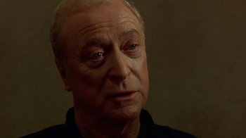 Movie still from “The Quiet American” (2002), directed by Phillip Noyce – An older man with a white beard and blue eyes looking at the camera; Close Up shot, Over the shoulder angle