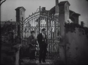 Movie still from “The Quiet Duel” (1949), directed by Akira Kurosawa – Two men are standing in front of an iron gate; Wide shot, Low angle
