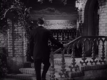 Movie still from “The Razor's Edge” (1946), directed by Edmund Goulding – A black and white photo of a man in a suit walking down a staircase; Wide shot, High angle