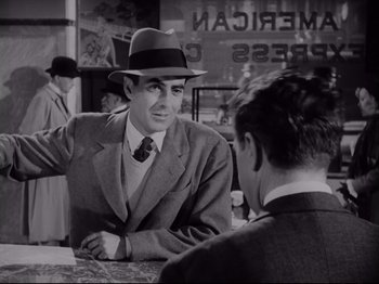 Movie still from “The Razor's Edge” (1946), directed by Edmund Goulding – A man wearing a suit and a hat talking to another man in a suit; Medium shot, Over the shoulder angle