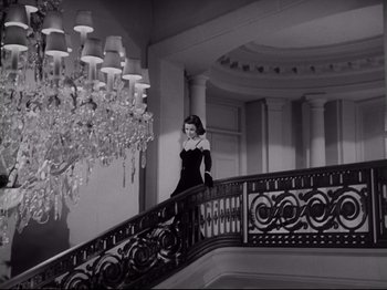 Movie still from “The Razor's Edge” (1946), directed by Edmund Goulding – A black and white photo of a woman walking down a staircase; Wide shot, Low angle
