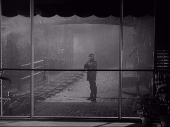 Movie still from “The Razor's Edge” (1946), directed by Edmund Goulding – A man taking a picture through a glass window; Wide shot, Low angle