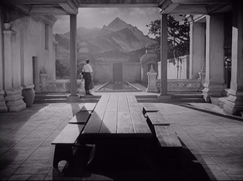 Movie still from “The Razor's Edge” (1946), directed by Edmund Goulding – A man standing next to a bench in front of a fountain; Extreme Wide shot, Low angle
