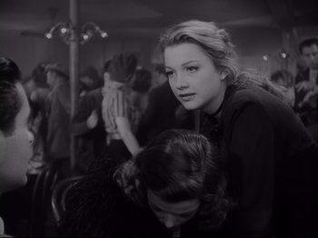 Movie still from “The Razor's Edge” (1946), directed by Edmund Goulding – A woman sitting next to another woman in a crowd; Medium shot, Over the shoulder angle