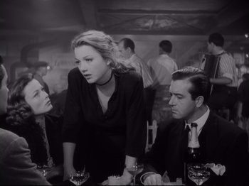 Movie still from “The Razor's Edge” (1946), directed by Edmund Goulding – A woman standing between two men at a table; Medium shot, Over the shoulder angle