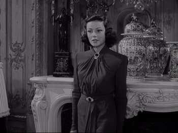 Movie still from “The Razor's Edge” (1946), directed by Edmund Goulding – A black and white photo of a woman standing in front of a fireplace; Medium shot, Low angle