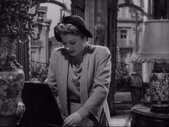 Movie still from “The Razor's Edge” (1946), directed by Edmund Goulding – A black and white photo of a woman looking at a laptop; Medium shot, Low angle