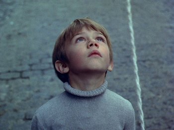 Movie still from “The Red Balloon” (1956), directed by Albert Lamorisse – A young boy looking up into the sky; Close Up shot, Low angle