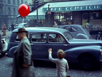Movie still from “The Red Balloon” (1956), directed by Albert Lamorisse – A man walking down the street with a red balloon in his hand; Extreme Wide shot, High angle