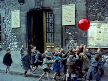 Movie still from “The Red Balloon” (1956), directed by Albert Lamorisse – A group of children playing with a red balloon; Wide shot, High angle