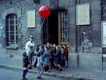 Movie still from “The Red Balloon” (1956), directed by Albert Lamorisse – A group of children walking down the street with a red balloon; Wide shot, High angle