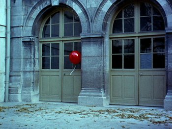 Movie still from “The Red Balloon” (1956), directed by Albert Lamorisse – A red balloon sitting in front of a building; Extreme Wide shot, Low angle