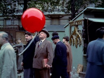Movie still from “The Red Balloon” (1956), directed by Albert Lamorisse – A group of people standing around a red balloon; Wide shot, High angle