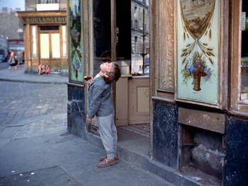 Movie still from “The Red Balloon” (1956), directed by Albert Lamorisse – A little boy standing in front of a building; Wide shot, High angle
