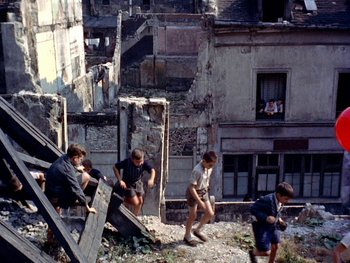 Movie still from “The Red Balloon” (1956), directed by Albert Lamorisse – A group of young men playing a game in the ruins; Wide shot, High angle