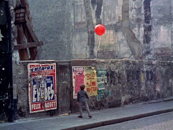 Movie still from “The Red Balloon” (1956), directed by Albert Lamorisse – A man walking down the street holding a red balloon; Extreme Wide shot, High angle