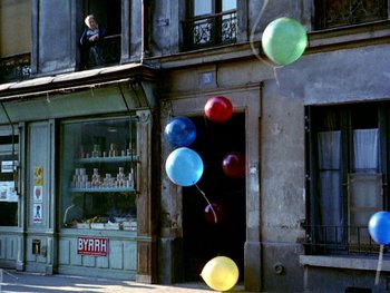 Movie still from “The Red Balloon” (1956), directed by Albert Lamorisse – A bunch of balloons floating in front of a building; Extreme Wide shot, High angle