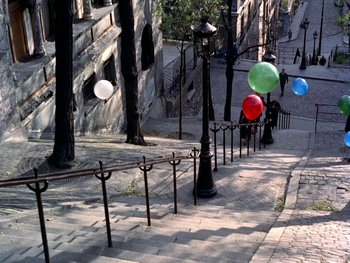 Movie still from “The Red Balloon” (1956), directed by Albert Lamorisse – A street scene with a bunch of balloons flying in the air; Extreme Wide shot, High angle