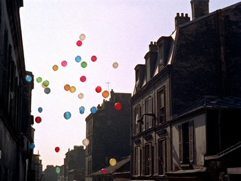 Movie still from “The Red Balloon” (1956), directed by Albert Lamorisse – A bunch of balloons floating in the air over some buildings; Extreme Wide shot, Low angle