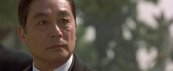 Movie still from “The Replacement Killers” (1998), directed by Antoine Fuqua – A person wearing a suit and tie; Close Up shot, Low angle