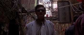 Movie still from “The Replacement Killers” (1998), directed by Antoine Fuqua – A man wearing a suit and tie standing in front of wires; Medium shot, Low angle