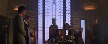 Movie still from “The Replacement Killers” (1998), directed by Antoine Fuqua – A man sitting at a table in front of a stained glass window; Wide shot, Low angle