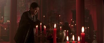 Movie still from “The Replacement Killers” (1998), directed by Antoine Fuqua – A man standing in front of a table filled with lit candles; Medium shot, Low angle
