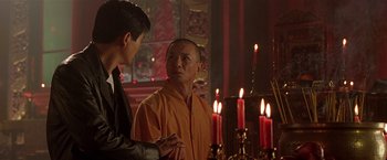 Movie still from “The Replacement Killers” (1998), directed by Antoine Fuqua – Two men standing in front of candles in a room; Medium shot, Over the shoulder angle