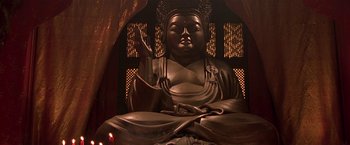 Movie still from “The Replacement Killers” (1998), directed by Antoine Fuqua – A large statue of a buddha sitting in front of a window; Medium shot, Low angle