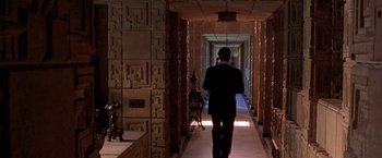 Movie still from “The Replacement Killers” (1998), directed by Antoine Fuqua – A man walking down a long hallway in a building; Wide shot, Over the shoulder angle