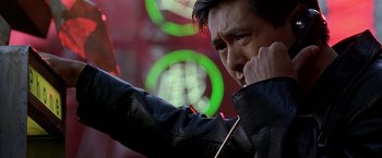 Movie still from “The Replacement Killers” (1998), directed by Antoine Fuqua – A man in a black jacket is talking on a cell phone; Close Up shot, Low angle