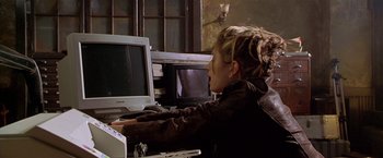 Movie still from “The Replacement Killers” (1998), directed by Antoine Fuqua – A woman sitting in front of a computer monitor; Medium shot, Over the shoulder angle