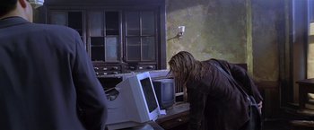 Movie still from “The Replacement Killers” (1998), directed by Antoine Fuqua – A woman looking at a computer monitor in an abandoned room; Medium shot, Over the shoulder angle