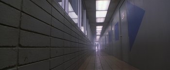 Movie still from “The Replacement Killers” (1998), directed by Antoine Fuqua – A person is walking down a hallway in a building; Wide shot, Low angle