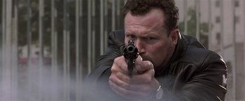 Movie still from “The Replacement Killers” (1998), directed by Antoine Fuqua – A man holding a gun while wearing a leather jacket; Close Up shot, Low angle