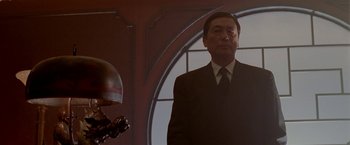 Movie still from “The Replacement Killers” (1998), directed by Antoine Fuqua – A man wearing a suit and tie standing in front of a mirror; Medium shot, Low angle