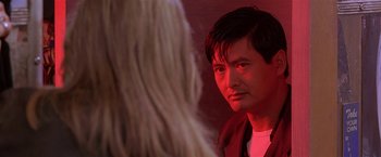 Movie still from “The Replacement Killers” (1998), directed by Antoine Fuqua – A man standing next to a woman in a red room; Close Up shot, Over the shoulder angle