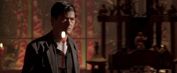 Movie still from “The Replacement Killers” (1998), directed by Antoine Fuqua – A man standing in front of a lit candle; Medium shot, Low angle