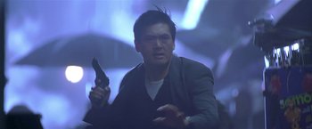 Movie still from “The Replacement Killers” (1998), directed by Antoine Fuqua – A man holding a gun in his hand and wearing a suit; Medium shot, Low angle